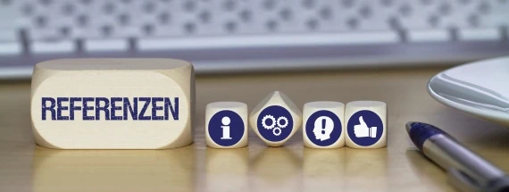 Vor einer Tastatur liegt ein Baustein mit dem Wort Referenzen
